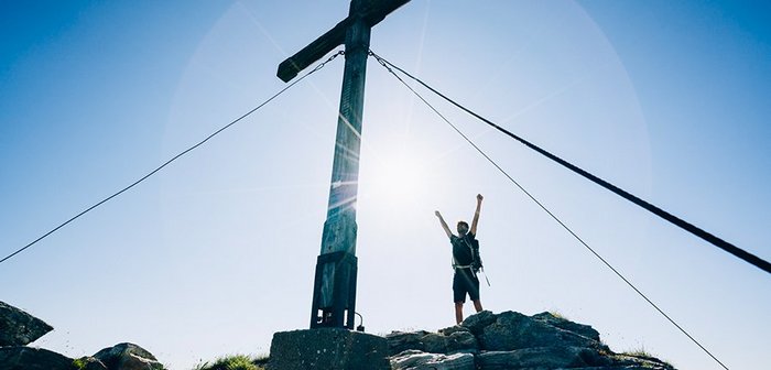Mann am Gipfel beim Gipfelkreuz