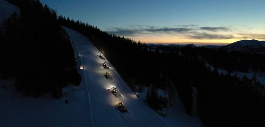 Pistenraupen präparieren Skipiste am Abend in den Bergen Österreichs