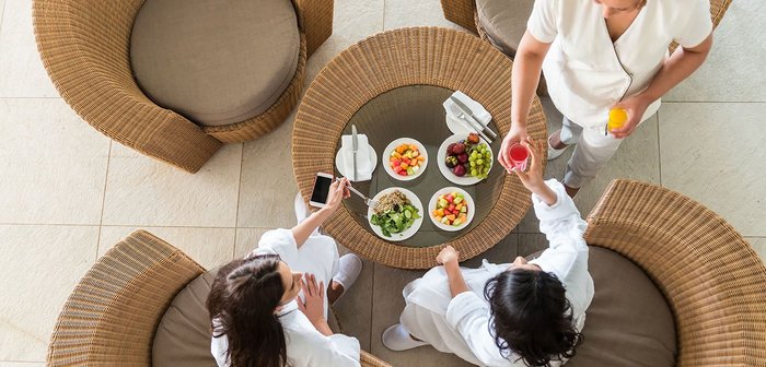 Zwei Frauen in Bademäntel genießen geschnittenes Obst und frischen Saft.