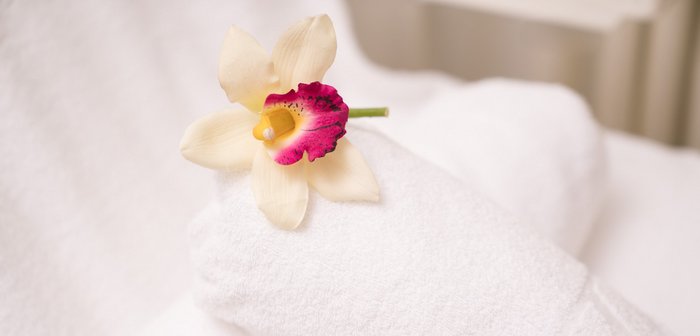 Massageliege und Handtücher mit Blumen in den modernen Massageräumen, im Thermal Römerbad Bad Kleinkirchheim