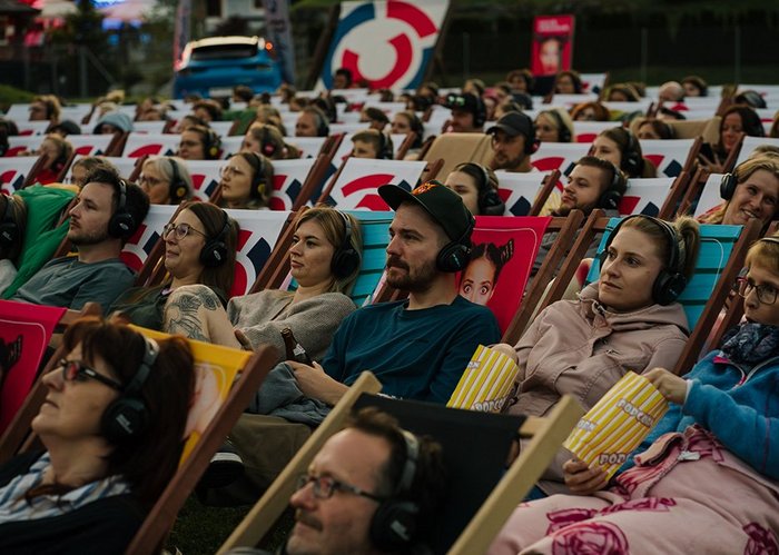Beim Silent Cinema sitzen mehrere Menschen mit Kopfhörern auf Liegestühlen und schauen einen Film.