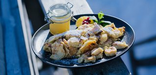 Kaiserschmarrn mit Apfelmus und Puderzucker auf schwarzem Teller