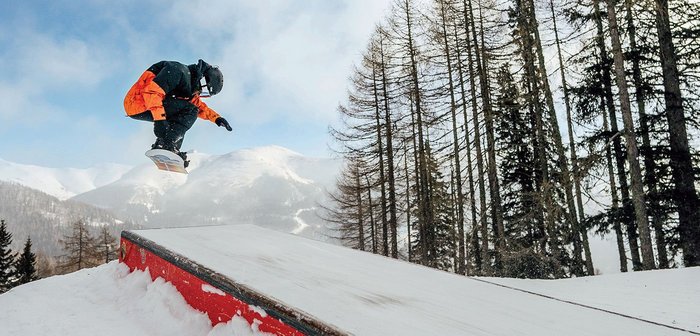 Ein Mann fährt Snowboard über eine Rampe.