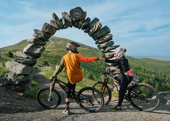 Steinernes Portal des längsten Flow Trails Europas, mit Mountainbike-Pärchen