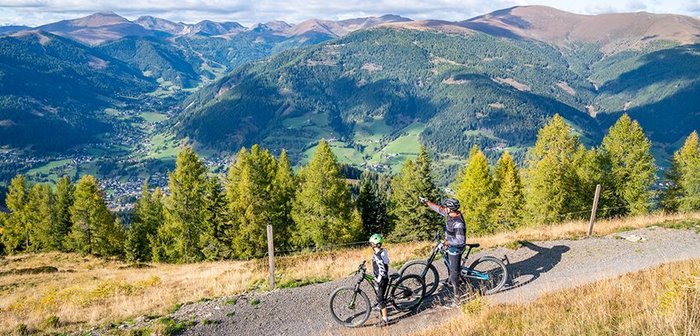 Zwei Mountainbiker blicken auf eine traumhafte Bergkulisse.