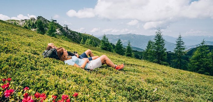 Ein Mann und eine Frau liegen in einer Wiese und beobachten die traumhafte Natur.