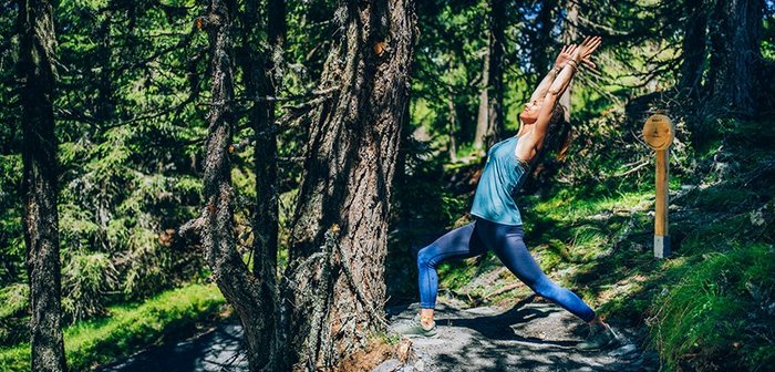 Eine Frau macht Yoga im Wald.