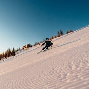 Sonnenaufgang in Bad Kleinkirchheim im Winter, Skifahrer auf Priedröfabfahrt, Nockberge Panorama in den österreichischen Alpen