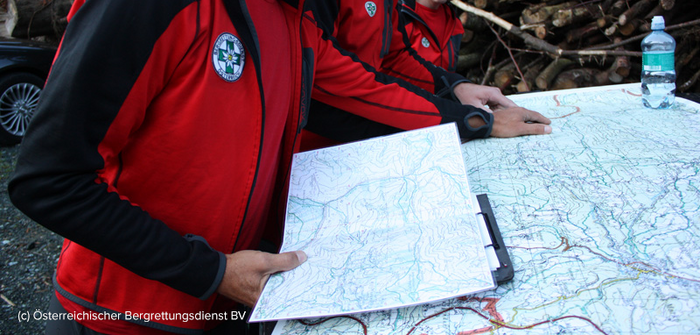 Teambesprechung der Bergrettung bei einem Einsatz, Lagebesprechung mit Routenkarte, Österreichische Bergrettung