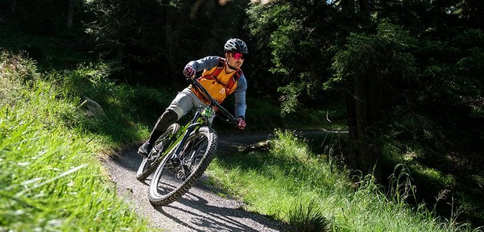 Ein Mountainbiker rast über einen Singletrail.