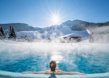 Winterurlaub, dampfendes Thermalwasser, Ausblick auf das Skigebiet Kaiserburg,  Therme Römerbad in Kärnten, Bad Kleinkirchheim