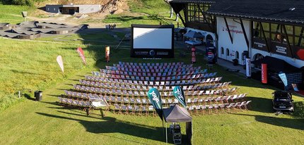 Freiluftkino mit vielen Sitzreihen und aufblasbarer Leinwand in einem Park