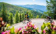 Biker Pärchen am Bad Kleinkirchheimer Flow Country Trail, blühender Almrausch in Kärnten