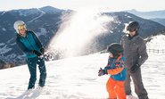 Ein Mann und eine Frau und ein Kind machen eine Schneeballschlacht.