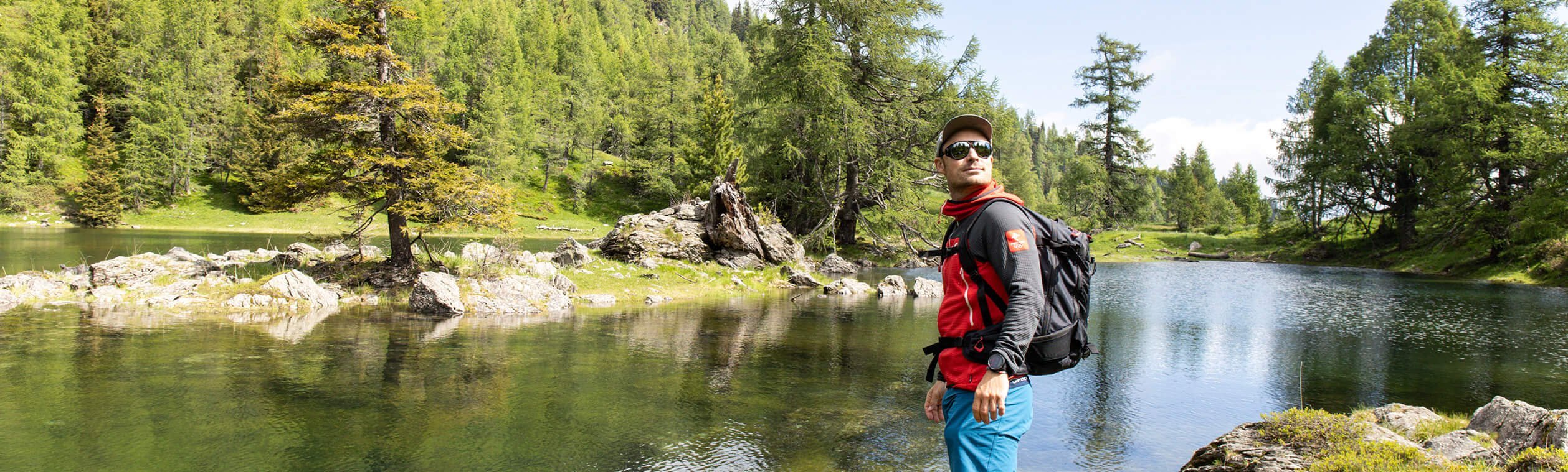 Ein Mann mit Sonnenbrille steht an einem See.