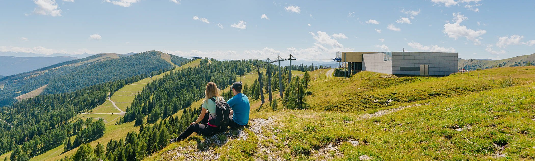 Ein Mann und eine Frau sitzen in einer Wiese und beobachten die traumhafte Natur.