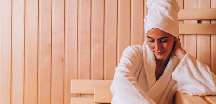 Eine Frau sitzt im Bademantel in der Sauna.