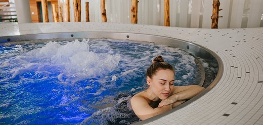 Frau entspannt im Whirlpool mit blauem Licht und Sprudelfunktion