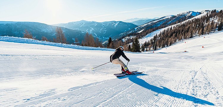 Skifahrerin auf präparierter Piste in den Kärntner Nockbergen bei Sonnenschein