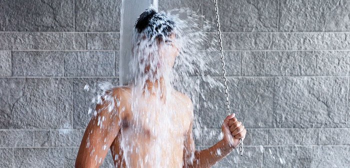 Ein Mann unter einer kalten Wasserdusche, zieht an einer Kette.