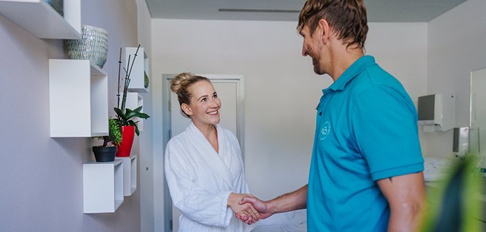 Ausgebildeter Heilmasseur Oliver begrüßt Kundin, kurzes Kennenlerngespräch und Fragenabklärung beim ersten Besuch