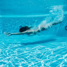 Frau im Bikini taucht im Thermalwasser des Thermal Römerbads