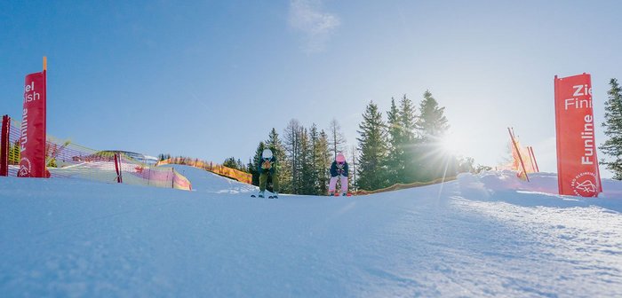 Zwei Skifahrer fahren eine Piste hinunter.
