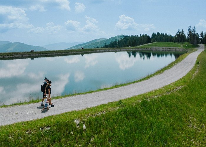 Familie spaziert am Rundweg um das Speicherbecken Brunnach, im Wandergebiet Bad Kleinkirchheim