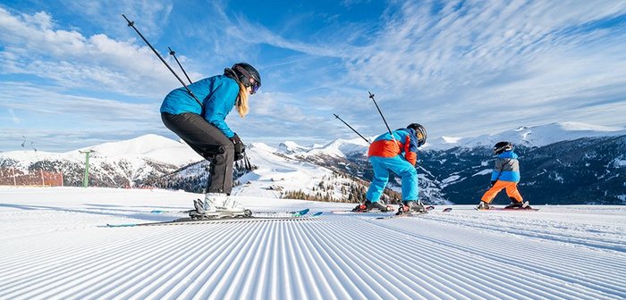 Familie auf der Panoramaabfahrt mit Blick auf den Nockalm Speichersee, im Top Kärntner Skigebiet Bad Kleinkirchheim