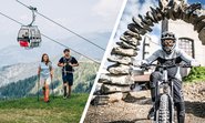 Wanderpärchen mit Kaiserburgbahn im Hintergrund, Mountainbiker vor dem Startportal des Flow Country Trails